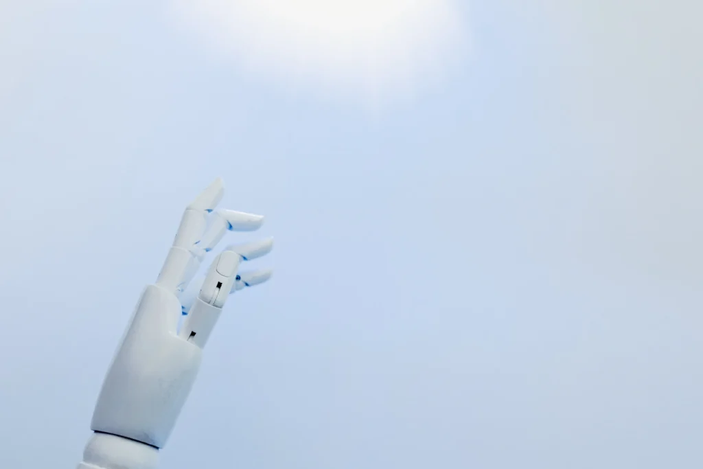 A white colored robotic hand with light blue color baackground.